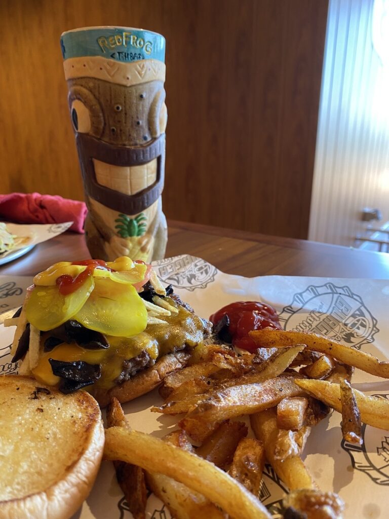 Guy's burger and fries plus a tiki mug on the Carnival mardi gras cruise ship.