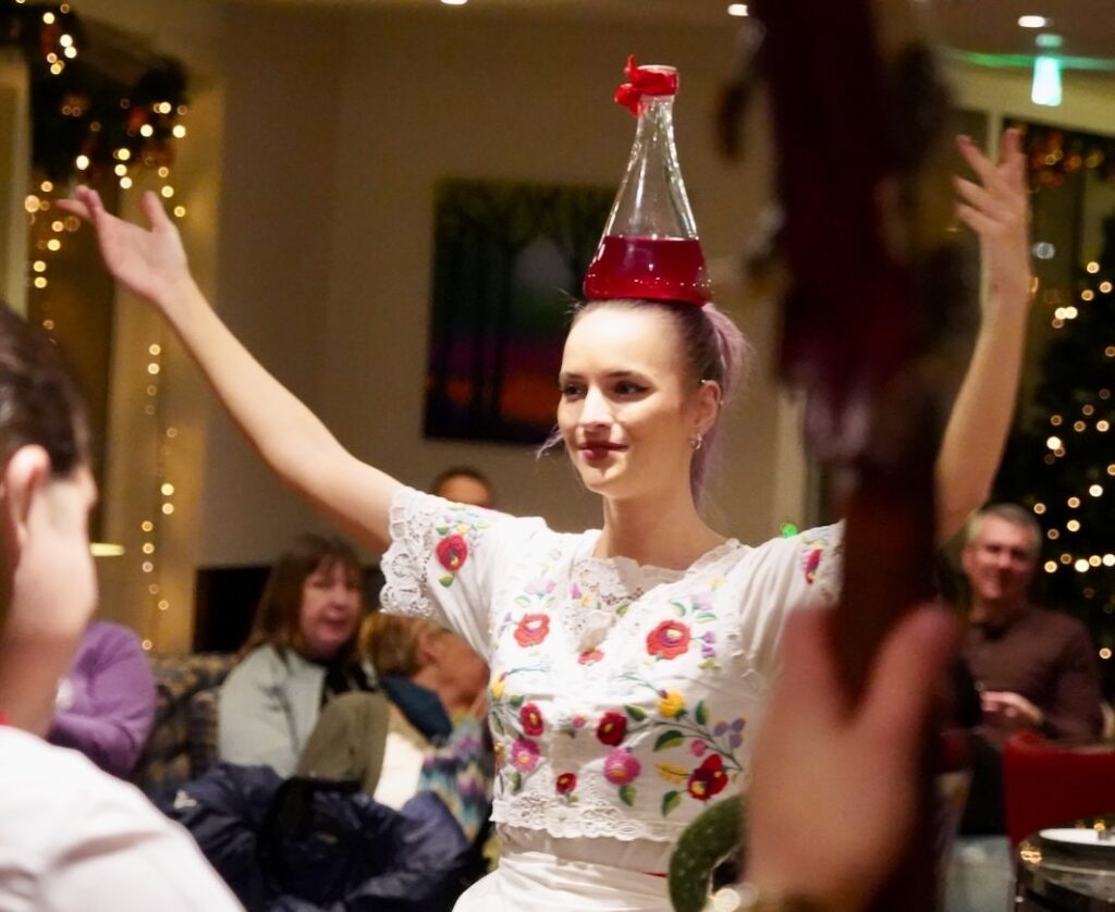 A guest performer balances a bottle of liquid on her head.